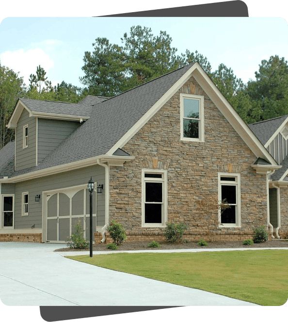 Stone house with gray roof and driveway.