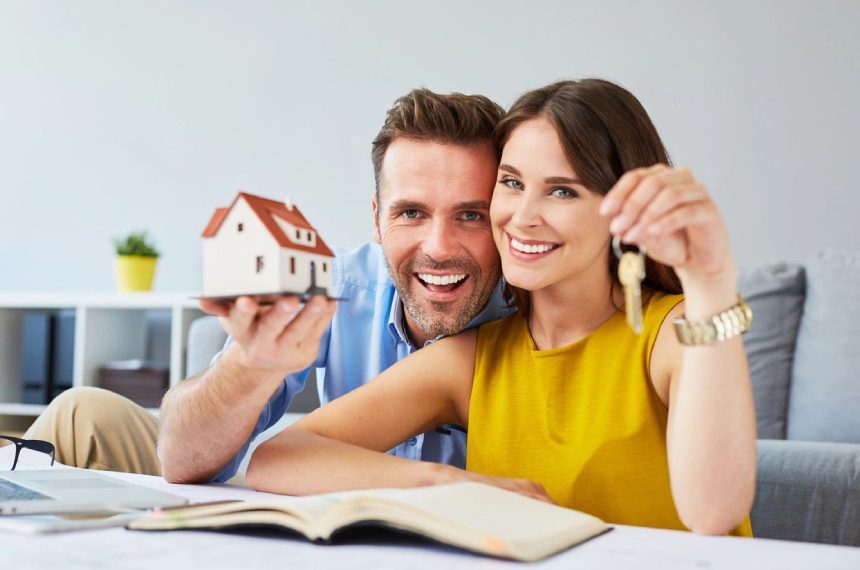 Happy couple holding house keys and model home.
